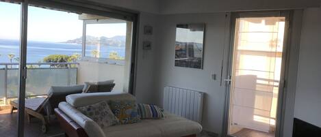 A modern living room with a sofa, a coffee table, and a view of the sea.