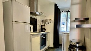 A compact kitchen with a refrigerator, microwave, stove, and a coffee maker. - 2-Room Apartment Near Sea, Air Conditioning, 4 Sleeps (Argelès-sur-Mer)