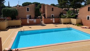 Une piscine rectangulaire bordée d’une terrasse carrelée, entourée d’immeubles aux murs de couleur beige et aux petites fenêtres.