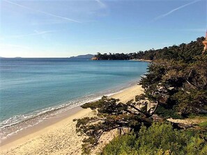A beach with clear blue water, sandy shore, and dense greenery. - Air-Conditioned 1-Bedroom Apartment with Pool, Wi-Fi, and Private Parking at Le Lavandou (Le Lavandou)