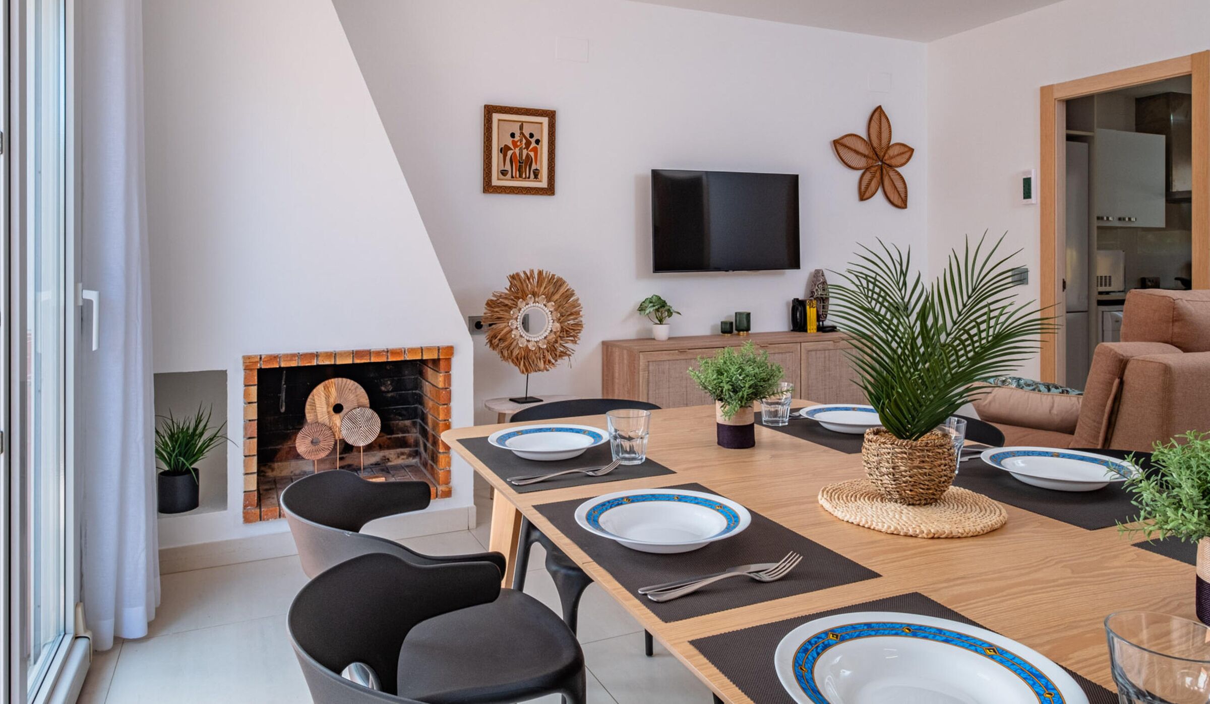 A modern dining area with a fireplace, a flat-screen TV, and a sofa.