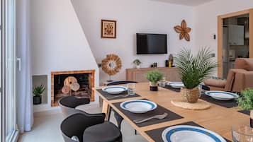 A modern dining area with a fireplace, a flat-screen TV, and a sofa.