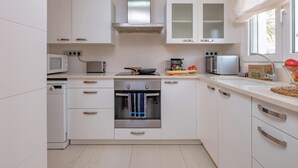 A modern kitchen with white cabinets, stainless steel appliances, and a window providing natural light. - Beachfront Family Retreat with Stunning Sea Views in Palamós (Palamós)