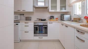 A modern kitchen with white cabinets, stainless steel appliances, and a window providing natural light.