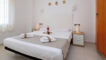 A hotel room with a large bed, two bedside tables, a nightstand, and a wooden door.