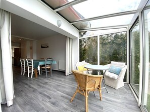 Enjoy meals and relaxation in this spacious room with a dining table, small table, and wicker chair.