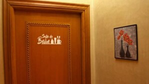 A wooden door with a sign reading "Salle de Bain." A framed picture of red flowers hangs on the wall to the right.