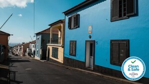 Eine Straße mit Gebäuden in Blau- und Beigetönen, mit Fensterläden und Balkonen.