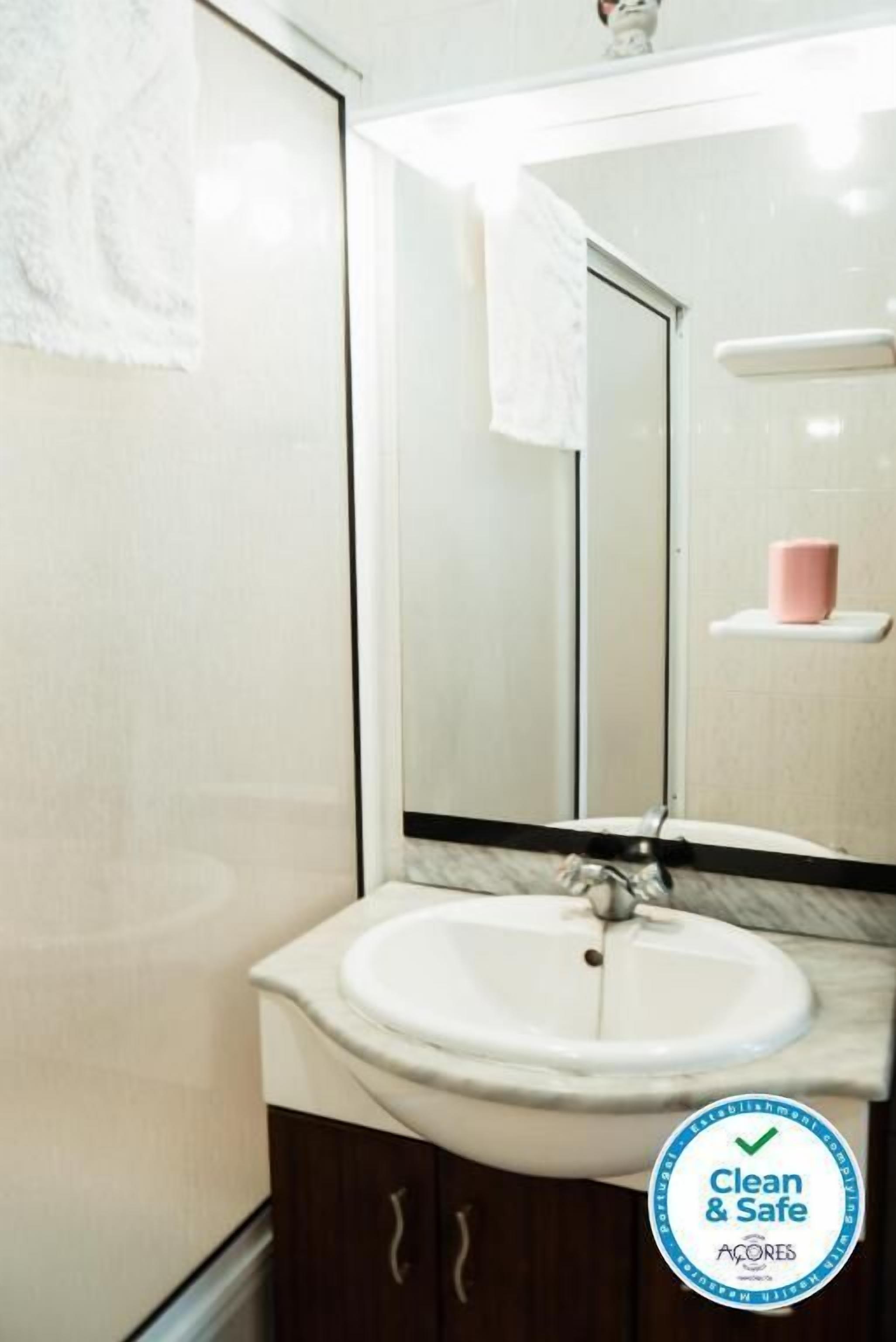 Une salle de bain avec un lavabo blanc, un miroir et une serviette accrochée au mur.