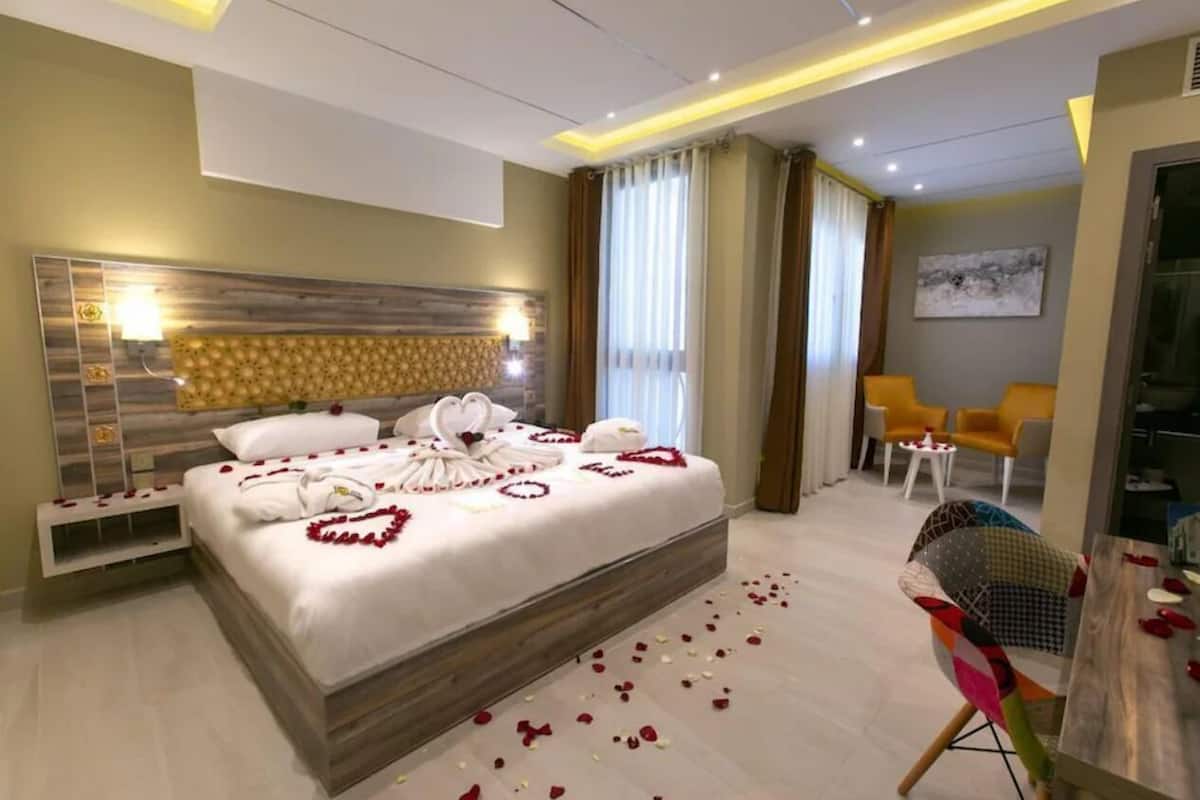 Una habitación de hotel moderna con una cama grande, una mesita de noche, una silla y una pequeña mesa con un jarrón.