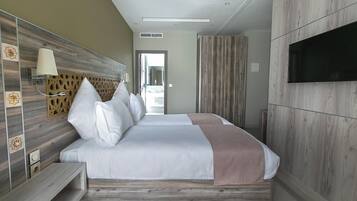 Una habitación de hotel moderna con una cama grande, un televisor montado en la pared y un tragaluz sobre la cama.