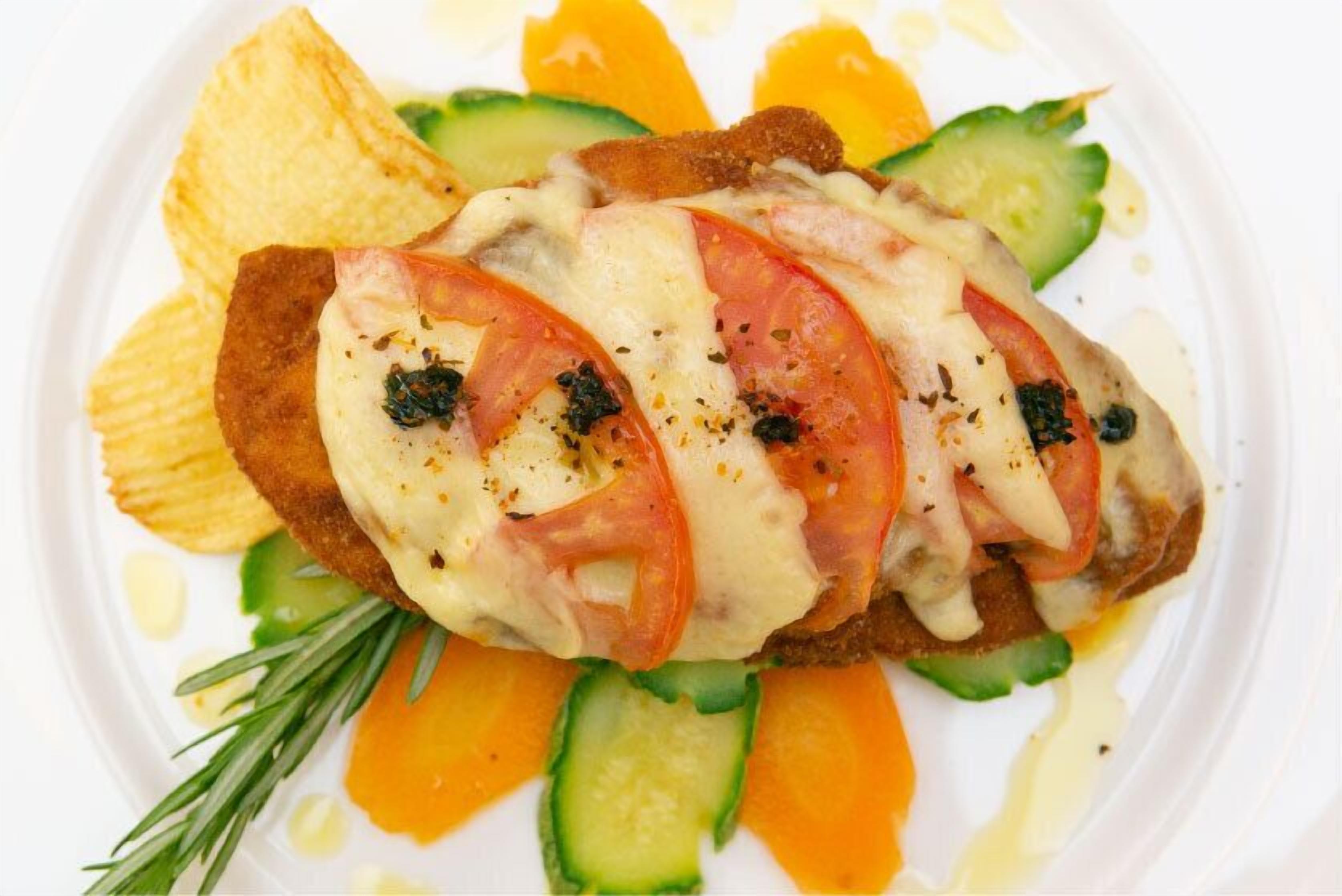 A dish with sliced tomatoes, cheese, and a garnish of rosemary.
