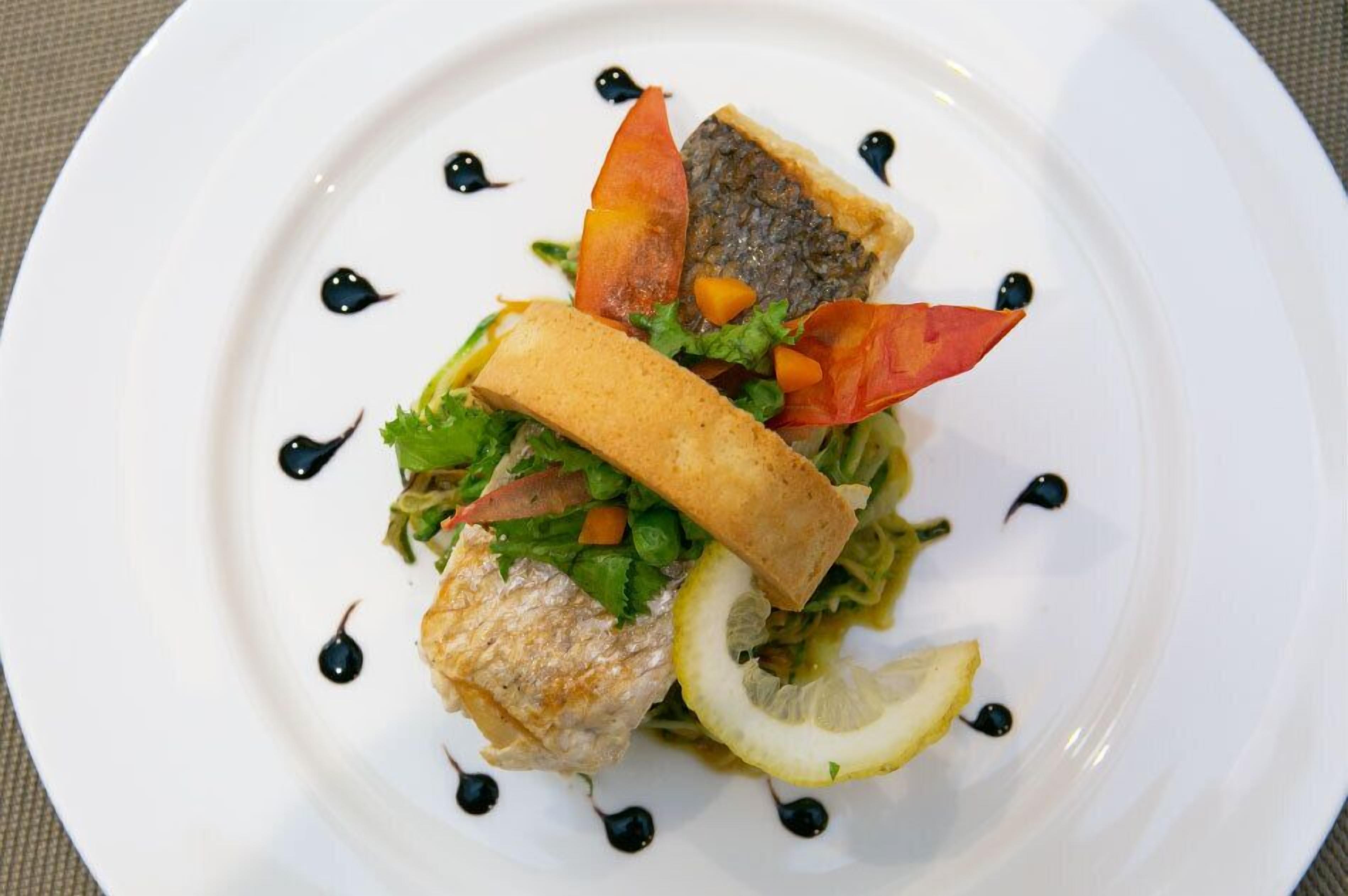 A plate with a sandwich, fish, and vegetables.