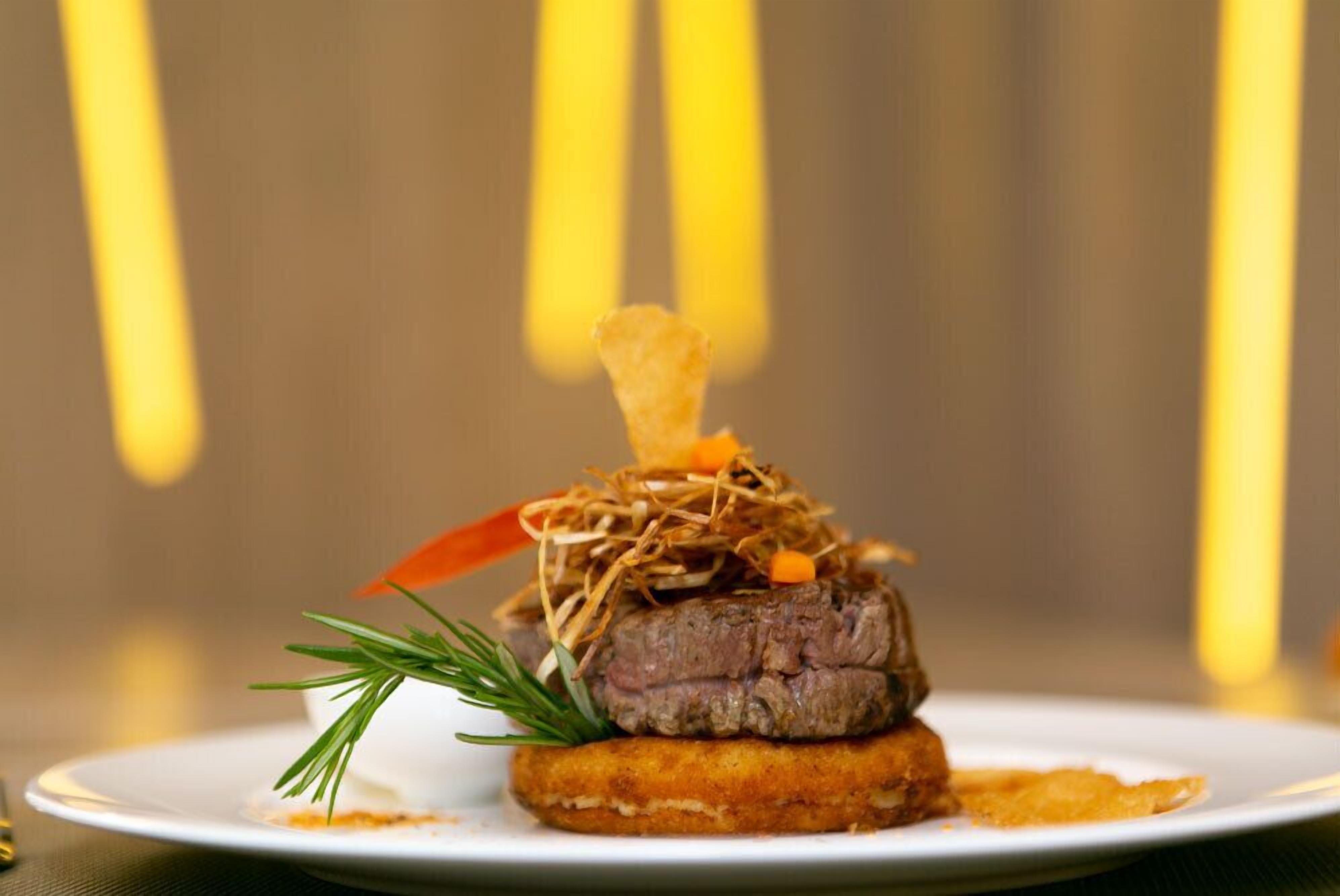 A plated dish with a piece of meat, garnish, and a side item.