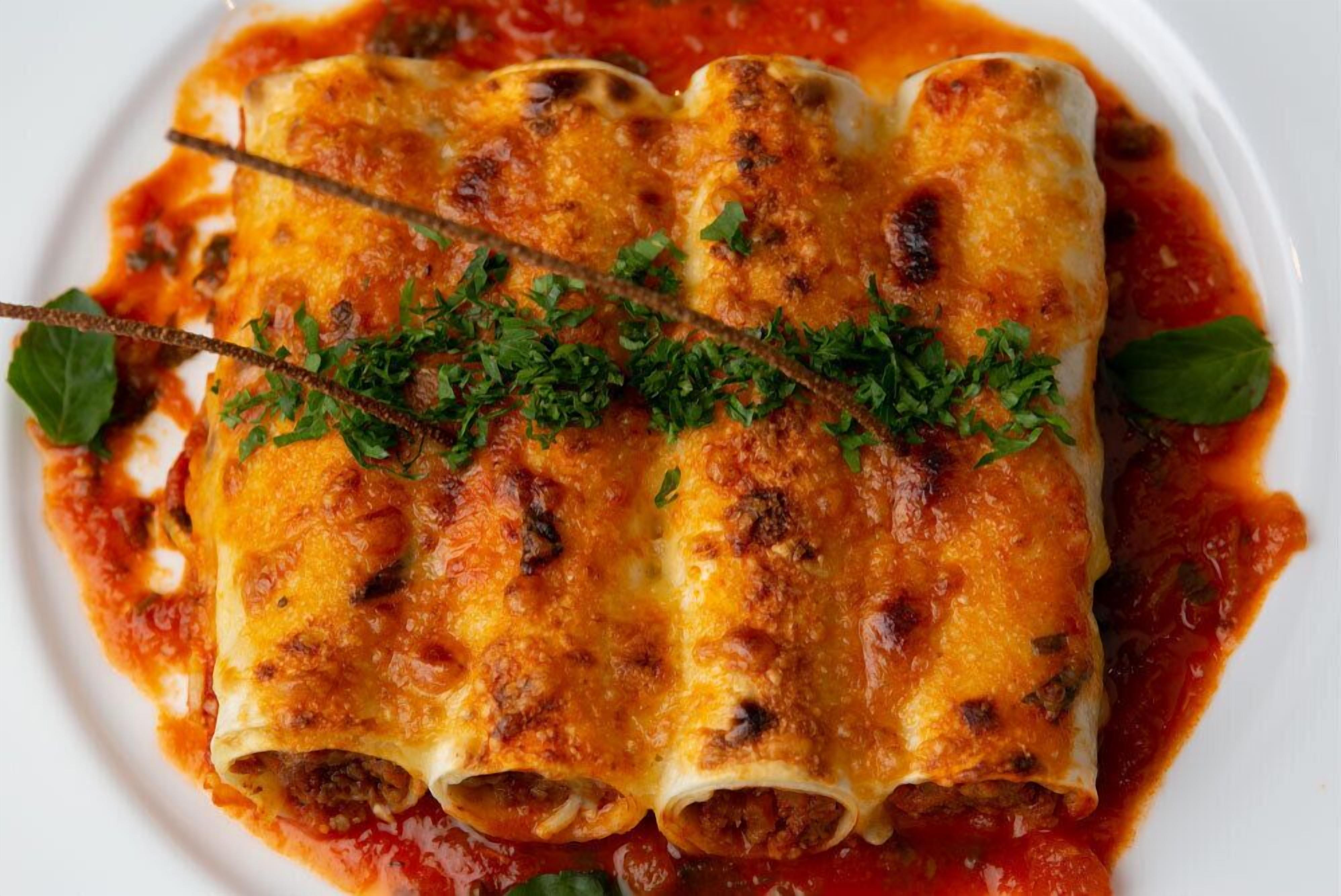 A plate of enchiladas topped with melted cheese and garnished with herbs.
