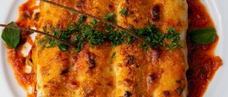 A plate of enchiladas topped with melted cheese and garnished with herbs.