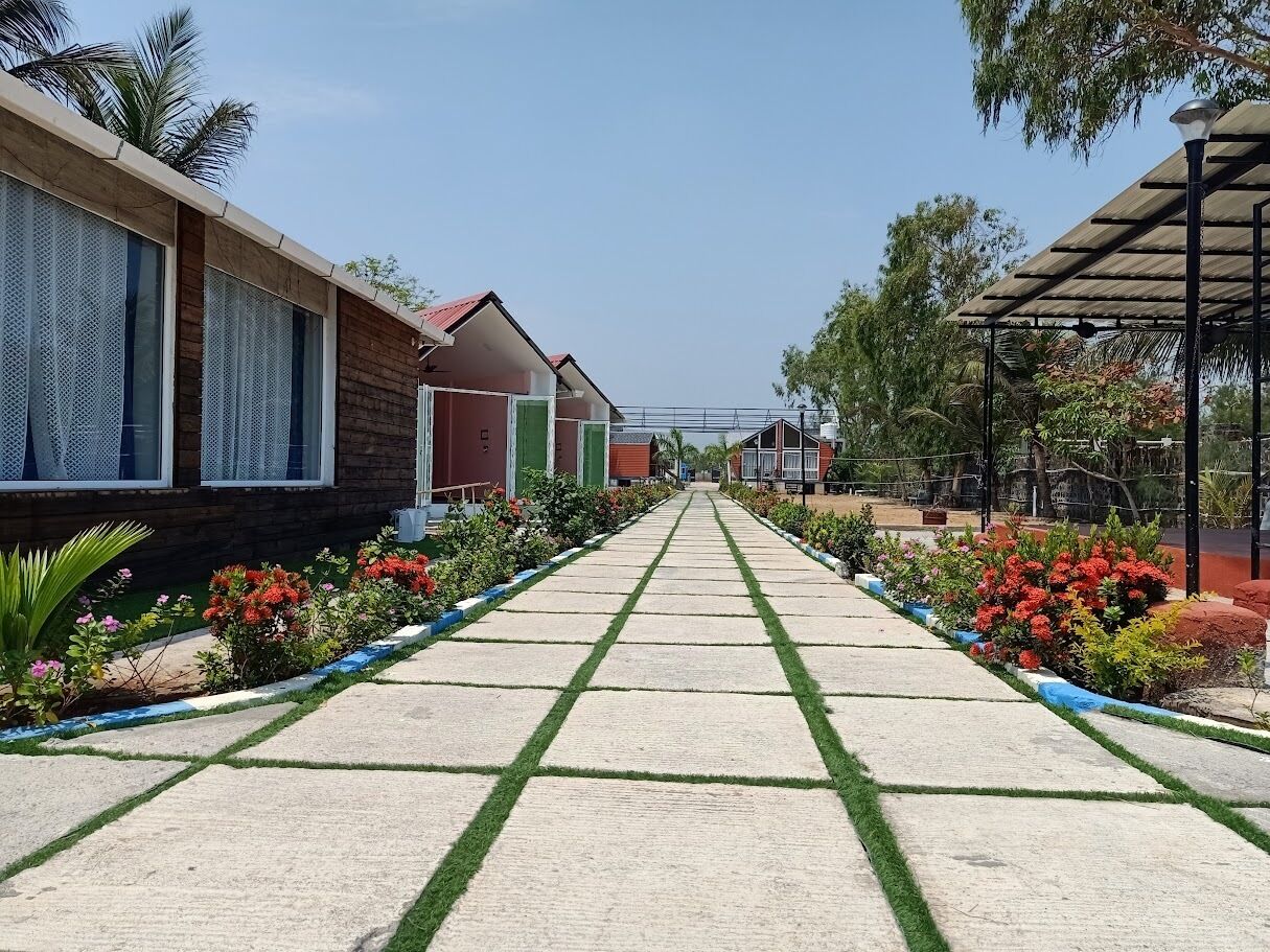 Ein Weg, gesäumt von bunten Blumenbeeten, mit einer Reihe Gebäude mit einheitlichem Baustil.