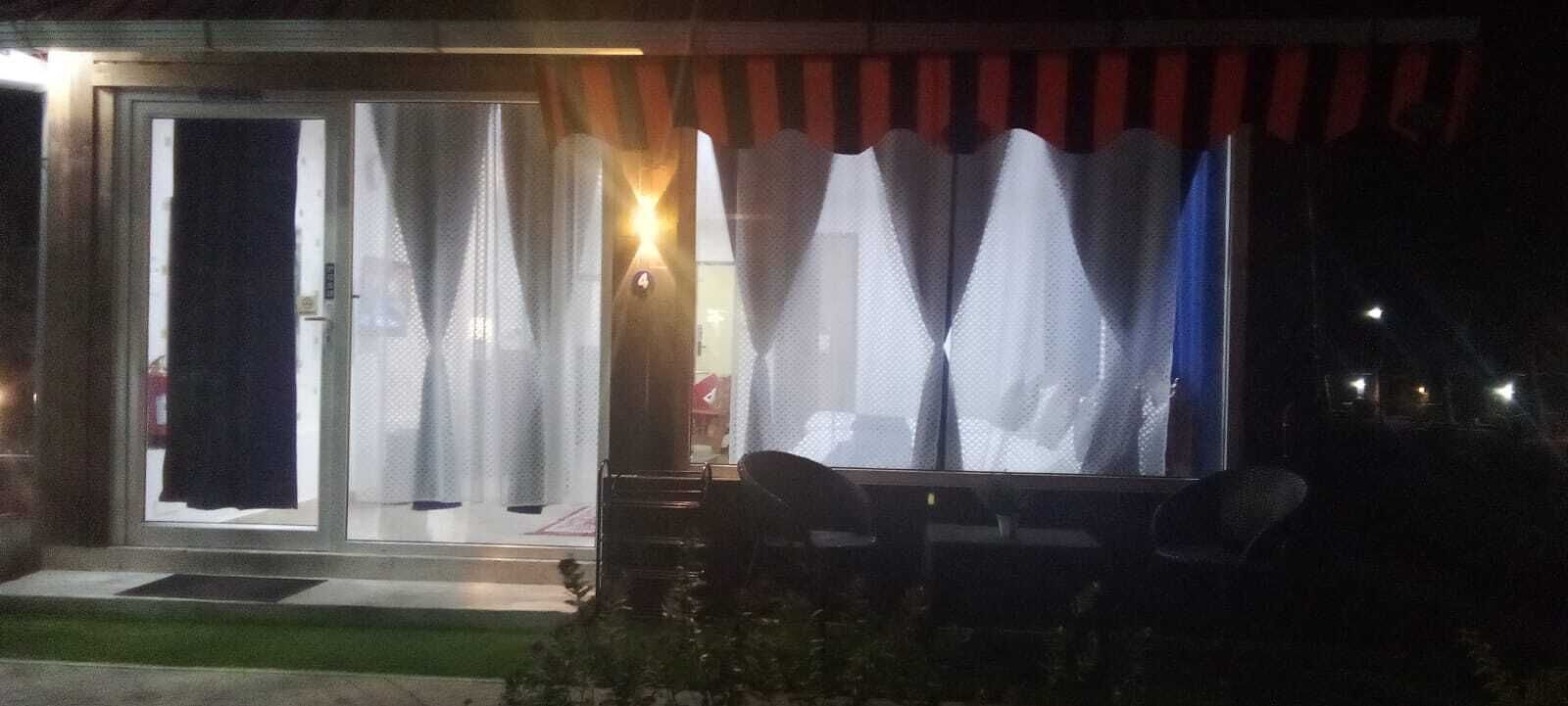 A building with a glass door, a covered outdoor seating area, and a small step leading to the entrance.