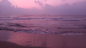 A beach with waves and a pink sky. - Chan Beach Resort (Bahur)