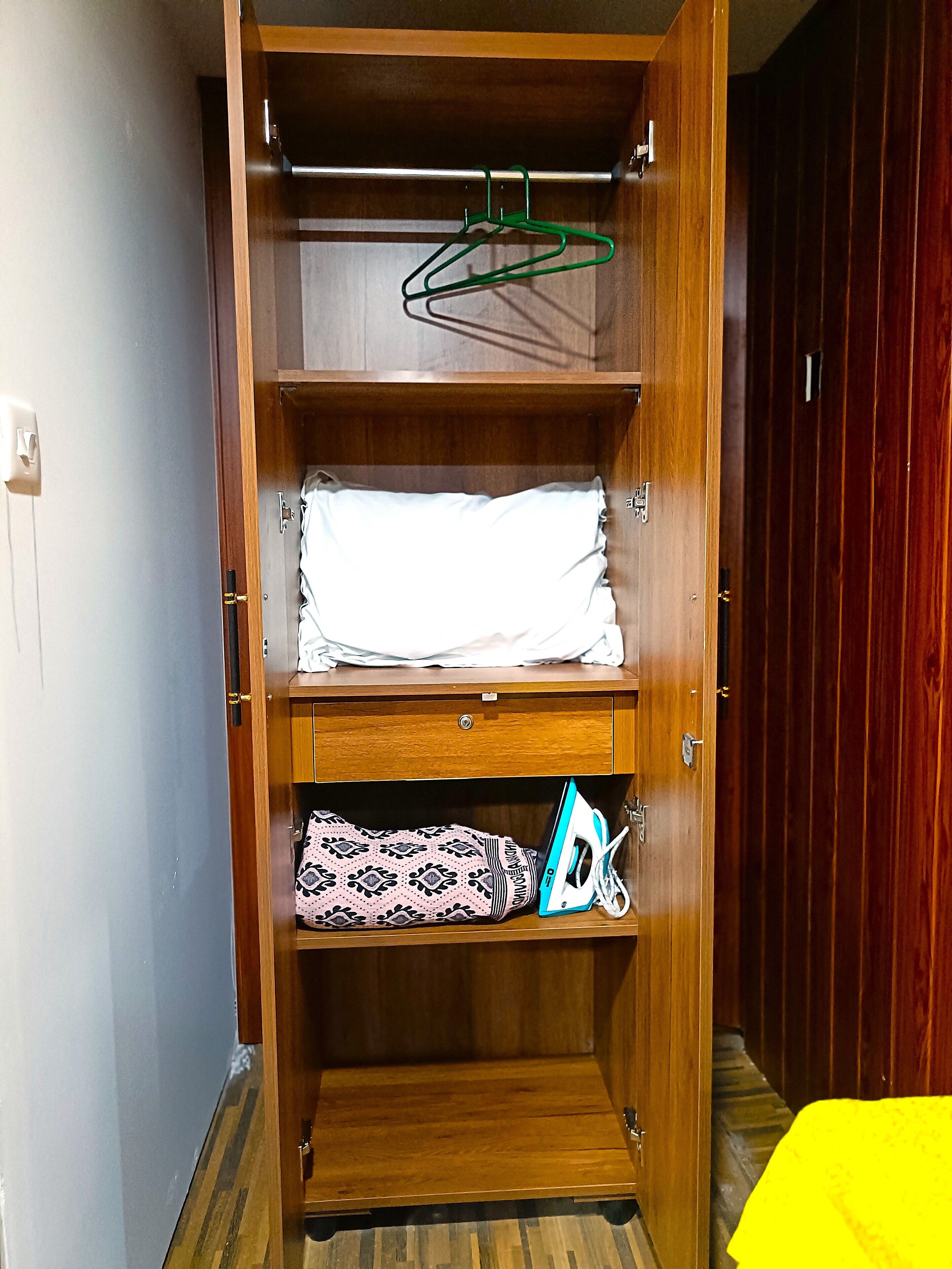 Een houten garderobe met twee planken, een kledingstang en een deur met een handgreep.