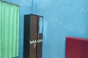 Una habitación con pared azul, cortina verde, armario de madera y sofá rojo.