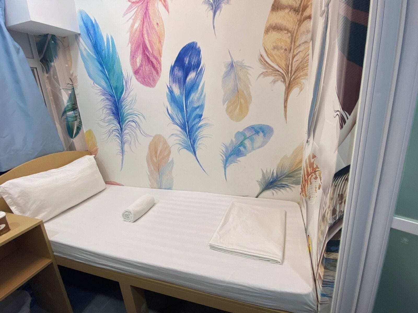 Cama bem arrumada com colchão branco e toalha branca dobrada.