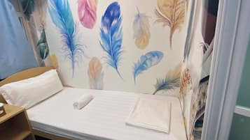 Cama bem arrumada com colchão branco e toalha branca dobrada.
