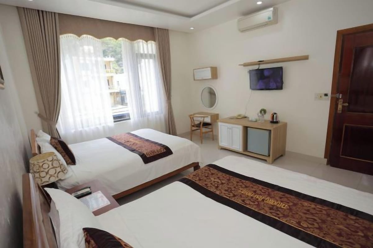 Ein Hotelzimmer mit zwei Betten, einem Schreibtisch, einem Fernseher und einem Kleiderschrank.