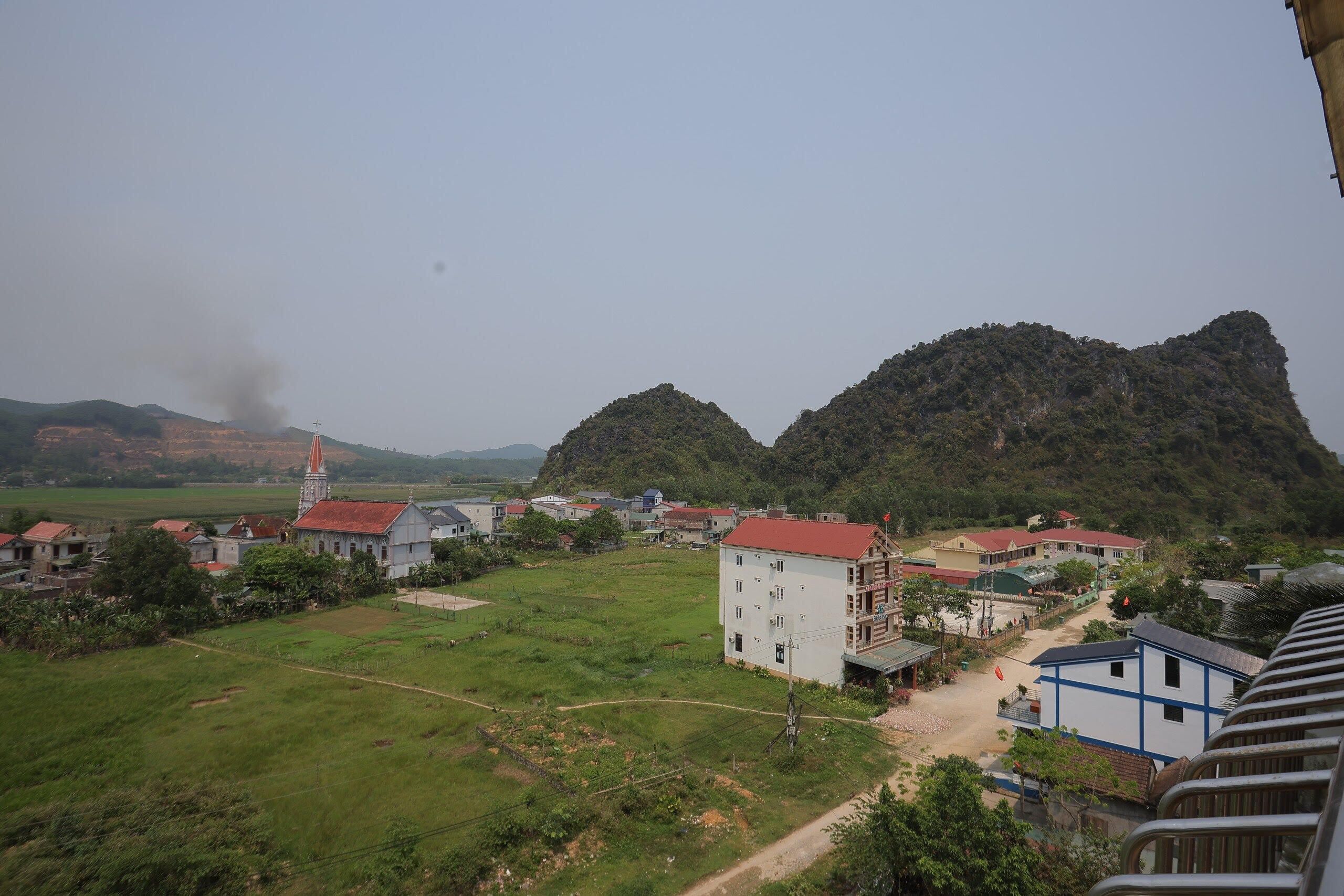 A rural village with buildings, a church, and mountains in the background.