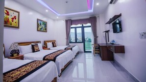 A hotel room with three beds, a desk, a TV, and a large window with a view. - Phong Nha Jasmine Hostel & Roof Top Bar (Phong Nha)