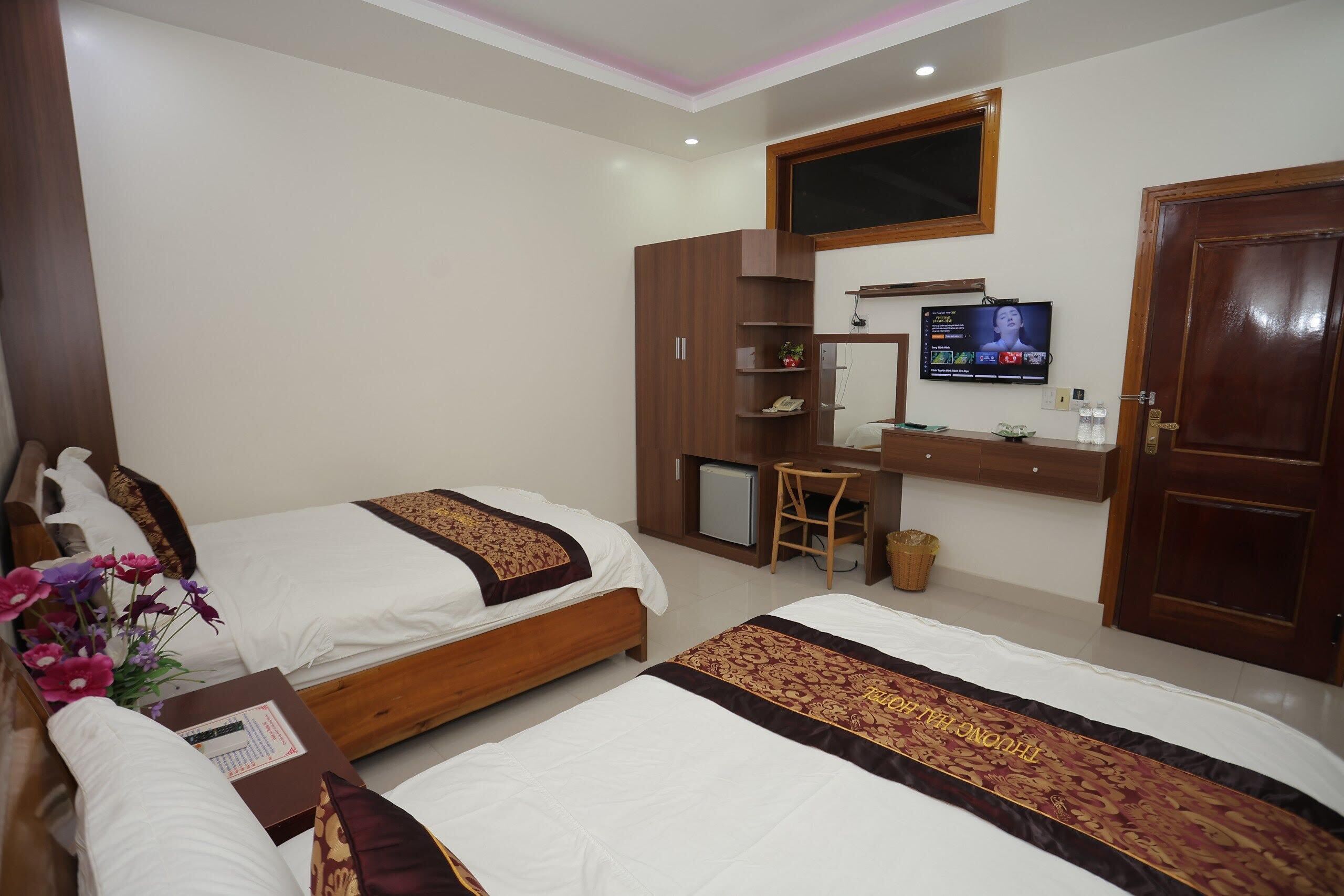 A hotel room with two beds, a desk, a television, and a wardrobe.