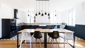 A modern kitchen with a wooden table, black chairs, and pendant lights. - Magnifique Loft Type Boutique Hôtel à Libourne (Libourne)