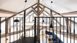 An attic room with exposed wooden beams, a black railing, and a view of the lower floor. - Magnifique Loft Type Boutique Hôtel à Libourne (Libourne)