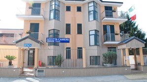 Un edificio de varios pisos con un cartel que dice “AFFITTA CAMERE” y “ENTRATA”, señalando una entrada.