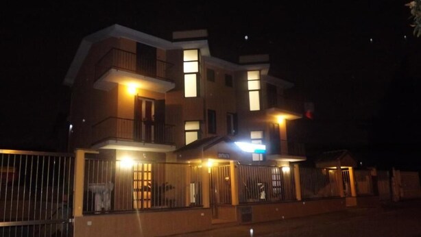 Un edificio de varios pisos con ventanas iluminadas y una entrada portonada de noche.