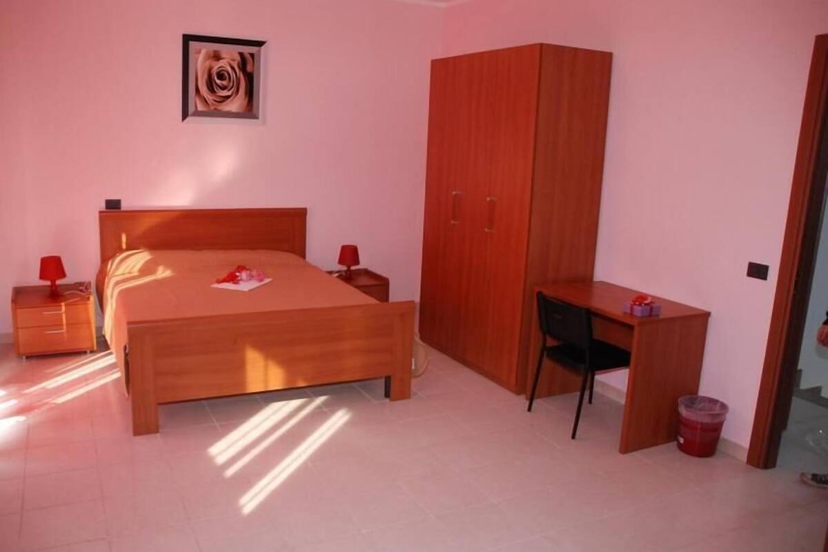 A bedroom with a wooden bed, a desk, and a wardrobe.