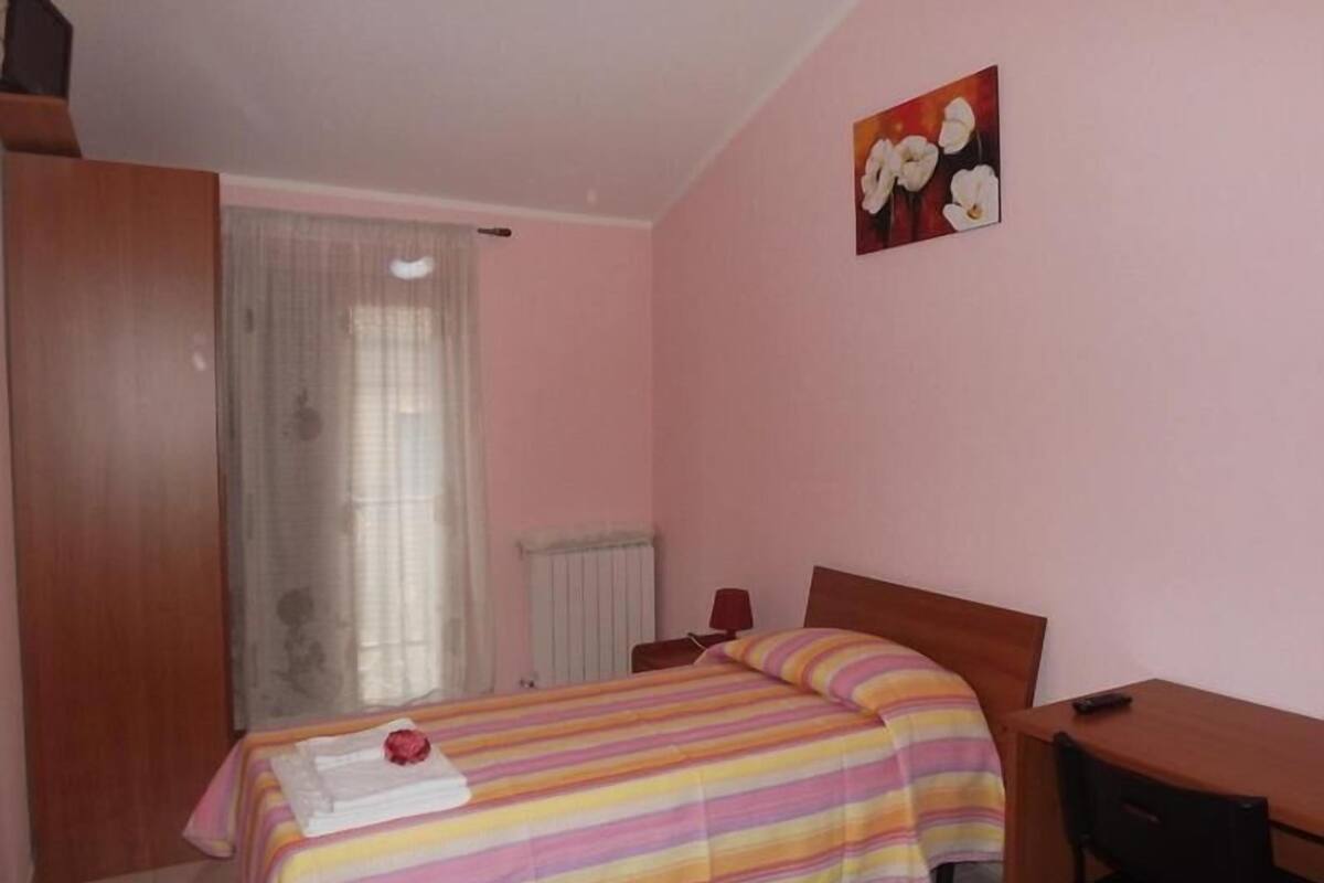 A bedroom with a bed, a desk, and a radiator.