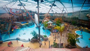 Un parc aquatique intérieur doté de plusieurs piscines, de toboggans et d’un espace couvert avec des sièges.