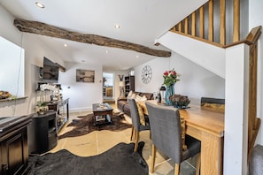 A modern living room with a dining area, a staircase, and a kitchen in the background. - Chic Cosy Rustic Barn Alton Towers Peaks (Stoke-on-Trent)