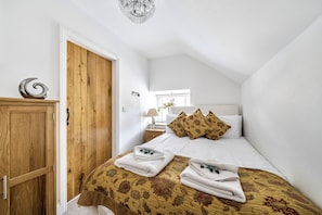 A bedroom with a bed, pillows, a bedside table, a lamp, and a wooden wardrobe. - Chic Cosy Rustic Barn Alton Towers Peaks (Stoke-on-Trent)