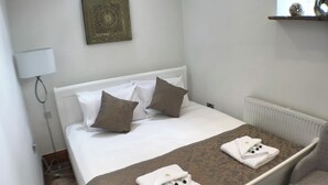 A neatly made bed with white and brown pillows, a patterned bedspread, and two folded towels on the footboard. - Sleeps 2 - Alton Towers, Scarefest, Peak District (Stoke-on-Trent)