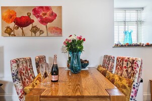 A dining table with a bottle of champagne, glasses, and a vase of flowers.
