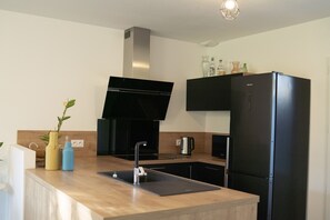 Eine moderne Küche mit einem schwarzen Herd, einem schwarzen Kühlschrank und einer Holz Arbeitsplatte.