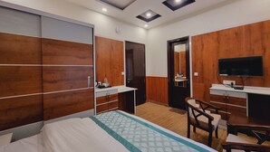 A modern hotel room with a bed, desk, chair, and a TV. - Stylia Suites (Dalhousie)