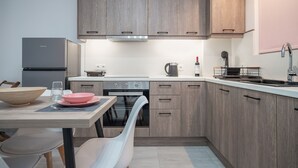 Een moderne keuken met houten kasten, een roestvrijstalen koelkast, een inbouwoven en een eethoek met een tafel en stoelen.