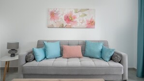 Een grijze bank met vier kussens in een woonkamer.