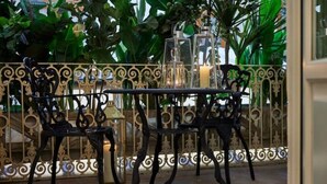 En terrasse med jernmøbler og lanterner med stearinlys, omgivet af frodigt grønt.