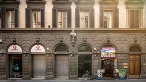 En bygning med flere Vodafone butiksskilte, lukket stormskrue og et turistinformation skilt.