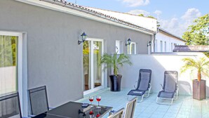 A patio with a table and chairs, a potted plant, and a door with glass panels.