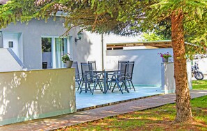 Une terrasse avec une table et des chaises, un pot de fleurs et un arbre.